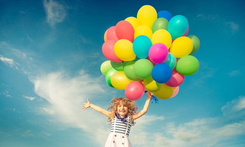 Happy child jumping with colorful toy balloons