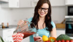 Happy young woman pouring vegetable smoothies